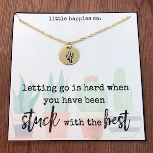 May include: A gold necklace with a small round pendant featuring a cactus design. The necklace is displayed on a card with the text "little happies co." and the quote "letting go is hard when you have been stuck with the best."