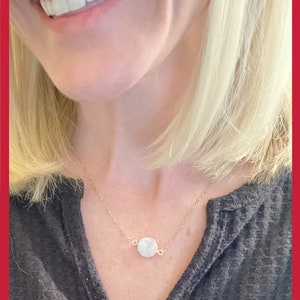 May include: A delicate gold chain necklace with a small, round, white gemstone pendant.