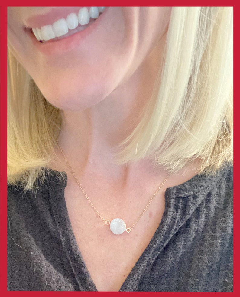May include: A delicate gold chain necklace with a small, round, white gemstone pendant.