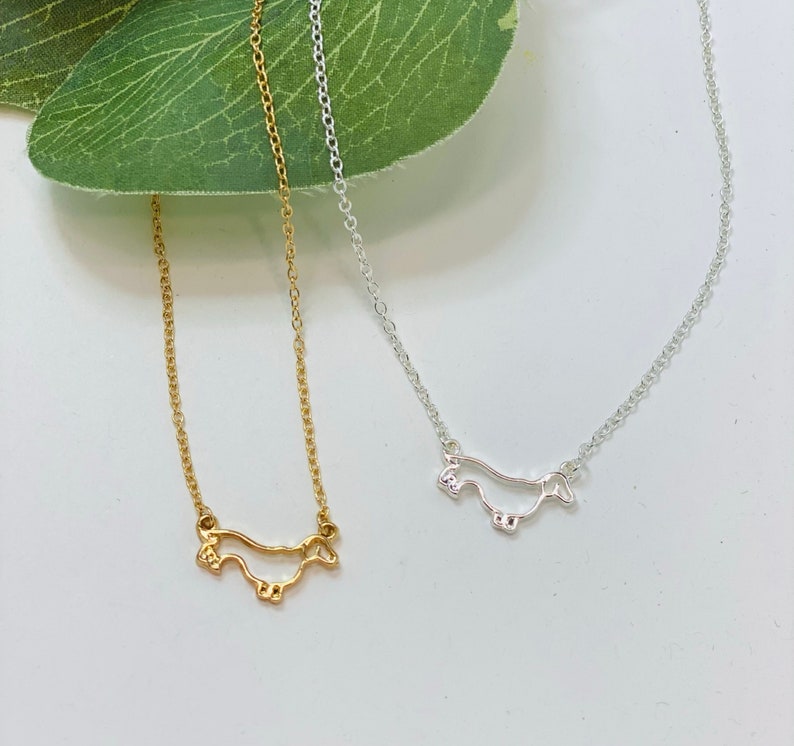 Peut inclure: Deux colliers d&eacute;licats avec des silhouettes de teckel. Un collier est en or et l'autre en argent.