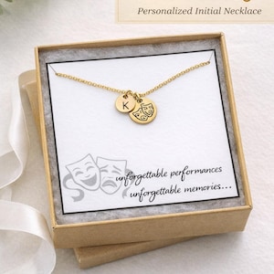 May include: Gold-colored necklace with two charms, one with the letter "K" and the other with drama masks. The necklace is in a gift box with the text "Perfect Drama Club Gift" and "Personalized Initial Necklace".
