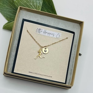 May include: Gold necklace with a runner charm and a small heart on a round disc. The necklace is in a gift box with a card that says "Little Happies Co." and "www.littlehappiesco.com".