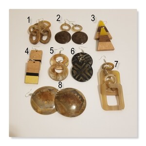 May include: Eight pairs of earrings made from wood, horn, and other natural materials. The earrings are in various shapes and sizes, including circles, squares, and triangles. The earrings are all in shades of brown, black, and yellow.