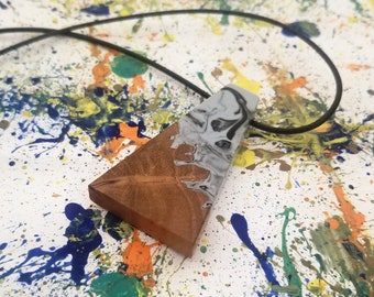 May include: A triangular pendant necklace with a wood and resin design. The resin is a swirl of white and black, and the wood is a light brown color.