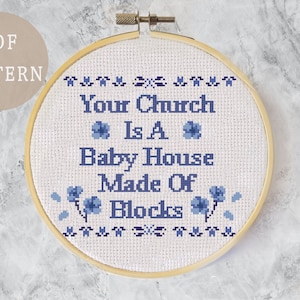 May include: A white embroidery hoop with blue floral accents and the text "Your Church Is A Baby House Made Of Blocks".