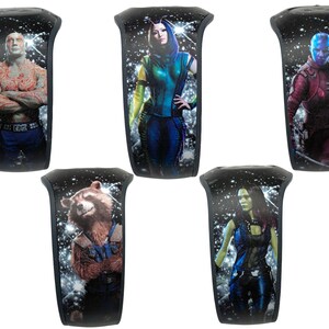 May include: Five different black wristbands with a space background and a character from the Guardians of the Galaxy movie series. The characters are: Drax, Gamora, Nebula, Rocket, and Mantis.