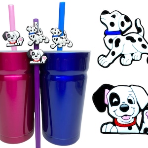 May include: Two insulated tumblers, one magenta and one blue, with matching straws. Each straw has a Dalmatian-themed charm. Additional Dalmatian charms are displayed separately. The charms feature black spots, red collars, and blue collars.