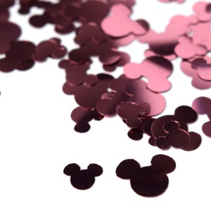 May include: Pink metallic Mickey Mouse confetti. The confetti is scattered on a white background.