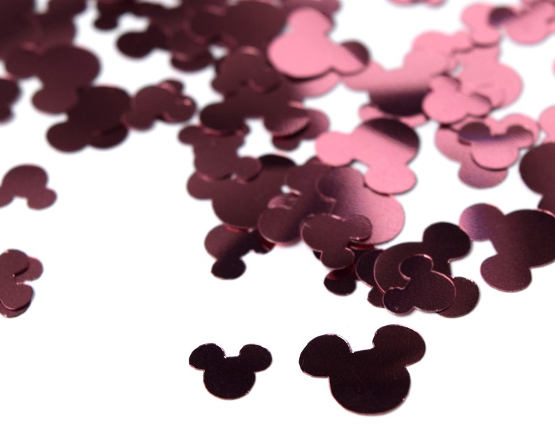 May include: Pink metallic Mickey Mouse confetti. The confetti is scattered on a white background.