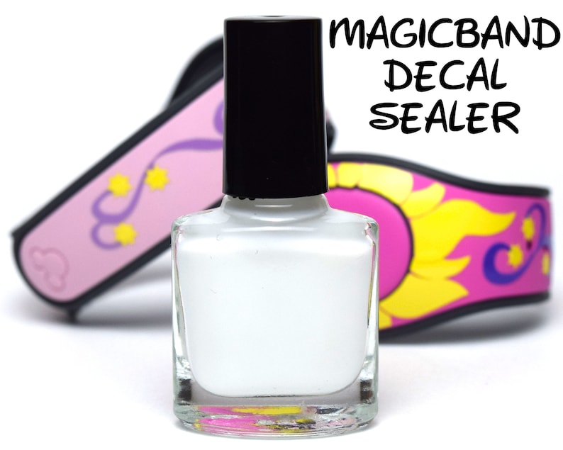 Może przedstawiać: Butelka białego Magicband Decal Sealer. Butelka jest przezroczysta i ma czarną zakrętkę. Butelka stoi na białym tle.
