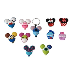 May include: A set of 11 colourful cartoon character charms, including Mickey Mouse, Minnie Mouse, cupcakes, and a monster. The charms are made of silicone and have a variety of designs.
