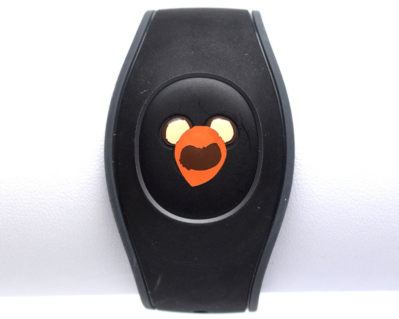 May include: Black MagicBand with a brown and orange Mickey Mouse head design.