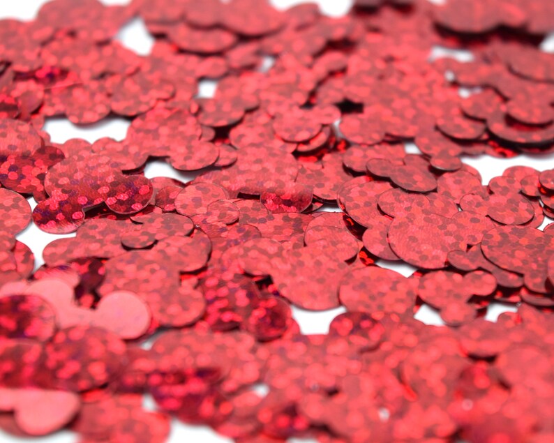 Op de afbeelding: Rode glitterconfetti in de vorm van harten. De confetti is verspreid over een wit oppervlak.