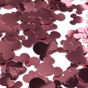 May include: A large pile of rose gold Mickey Mouse confetti. The confetti is made of thin, shiny material and is perfect for adding a touch of sparkle to any party or celebration.