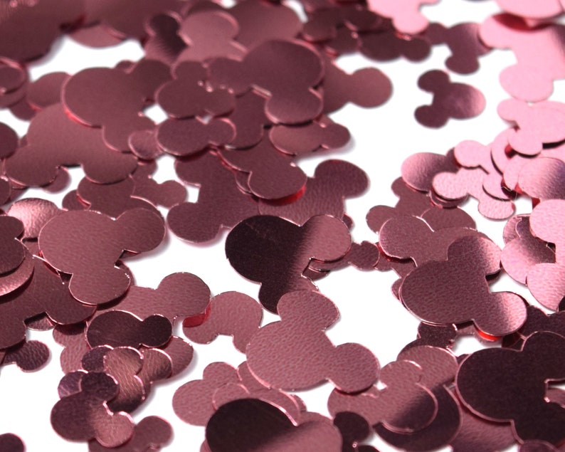 May include: A large pile of rose gold Mickey Mouse confetti. The confetti is made of thin, shiny material and is perfect for adding a touch of sparkle to any party or celebration.