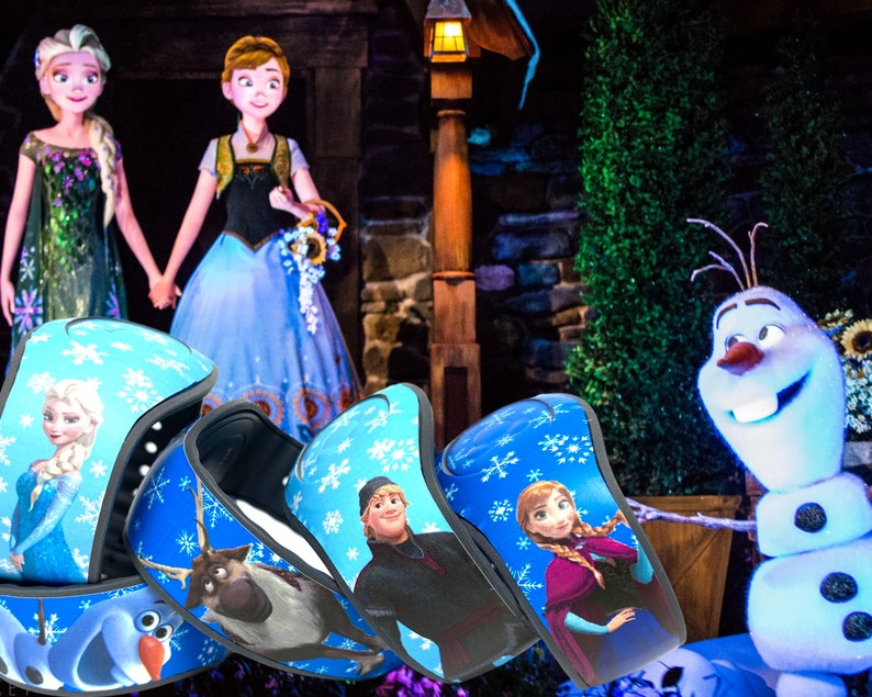 May include: Blue wristbands featuring characters from the animated film "Frozen", including Elsa, Anna, Olaf, and Kristoff. The wristbands have a blue background with snowflake patterns. The background shows the characters Elsa and Anna, and Olaf the snowman.