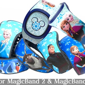 May include: Several blue MagicBand 2 and MagicBand+ wristbands featuring characters from the movie Frozen. The bands have images of Elsa, Anna, Olaf, Kristoff, and Sven, with snowflake and Mickey Mouse designs. Text at the bottom reads "for MagicBand 2 & MagicBand+".