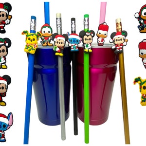 Peut inclure: Ensemble de six sur-pointe de crayon à thème de Noël. Les sur-pointe présentent Mickey Mouse, Donald Duck, Stitch et un chien jaune. Les sur-pointe sont attachés à des crayons de différentes couleurs, notamment bleu, vert, argent et or. Les crayons sont placés devant un gobelet bleu et rose.