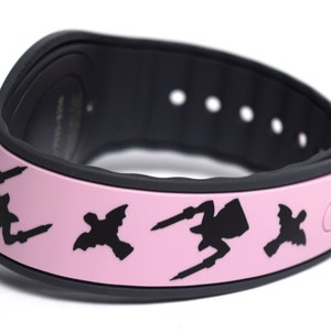 May include: Pink MagicBand with black silhouettes of the Disney villains Maleficent, Ursula, and Cruella de Vil. The band has a black Mickey Mouse icon on the right side.