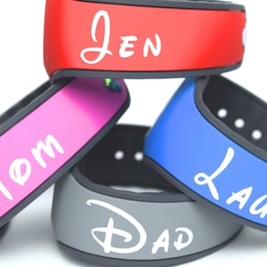 May include: Four colorful Disney MagicBands with personalized names: Jen, Mom, Dad, and Lauri. The bands are stacked on top of each other, with the red band on top and the gray band on the bottom.