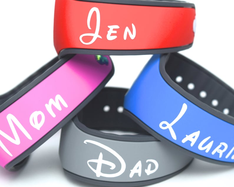 May include: A stack of four silicone wristbands with black inner bands and colored outer surfaces in red, pink, blue, and gray. The red band features the white text "Jen", the pink band says "Mom", the blue band says "Laurie", and the gray band says "Dad".