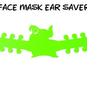 May include: Green plastic face mask ear saver with a cartoon monster design. The ear saver has multiple holes for adjusting the length.
