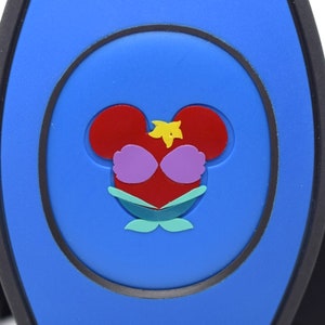 May include: A blue plastic Disney MagicBand with a red, yellow, and green Ariel the Little Mermaid character design.