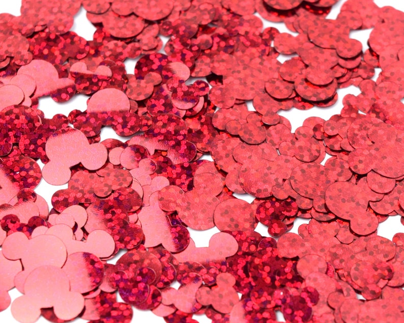 Op de afbeelding: Rode glitterconfetti in de vorm van Mickey Mouse-koppen. De confetti is verspreid over een witte achtergrond.