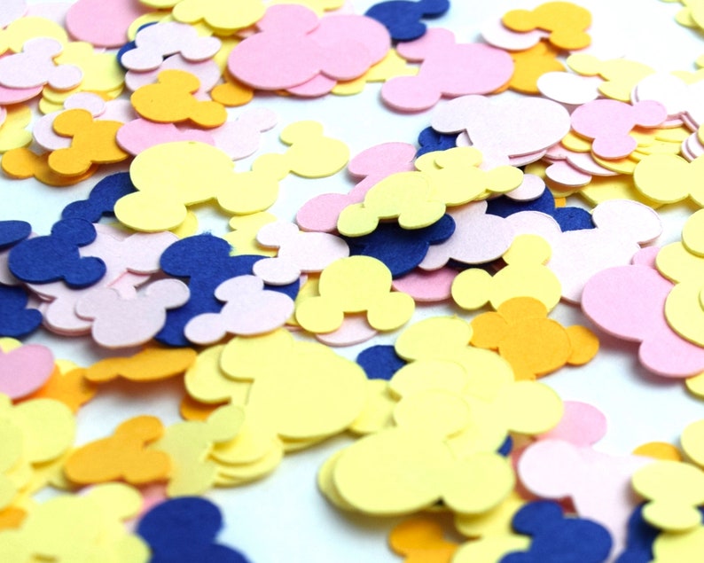 Puede incluir: Una dispersi&oacute;n de confeti en forma de cabezas de Mickey Mouse. El confeti es en tonos de amarillo, rosa y azul.