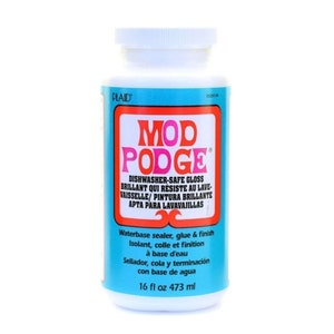 Może przedstawiać: Biała butelka Mod Podge Dishwasher-Safe Gloss, wodny środek uszczelniający, klej i wykończenie. Butelka jest niebieska i biała z nazwą produktu w czerwonych i r&oacute;żowych literach. Butelka zawiera 16 uncji płynu lub 473 mililitr&oacute;w.
