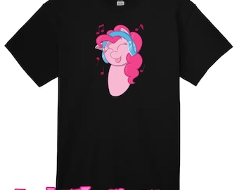 Op de afbeelding: Zwart T-shirt in kindermaat met een roze cartoonpaard dat blauwe koptelefoon draagt en naar muziek luistert. Het paard heeft een roze manen en staart en is omringd door muzieknoten.