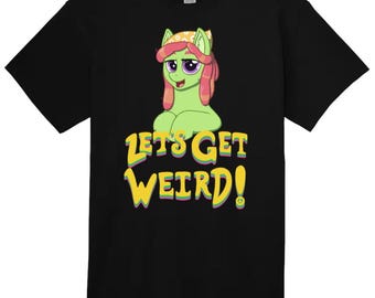 Op de afbeelding: Zwart t-shirt met een cartoon pony in groen, roze en geel. De tekst "LET'S GET WEIRD!" is geel met een paarse omlijning. Een vredesteken staat aan het einde van de tekst.