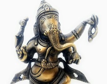May include: A bronze-colored statue of the Hindu deity Ganesha, depicted dancing. The statue features intricate details, including a crown, multiple arms holding various objects, and is mounted on a decorative base with animal figures.