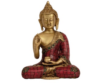 May include: A gold-colored Buddha statue sitting in a meditative pose with a red and gold patterned robe. The statue is holding a small bowl in its lap.