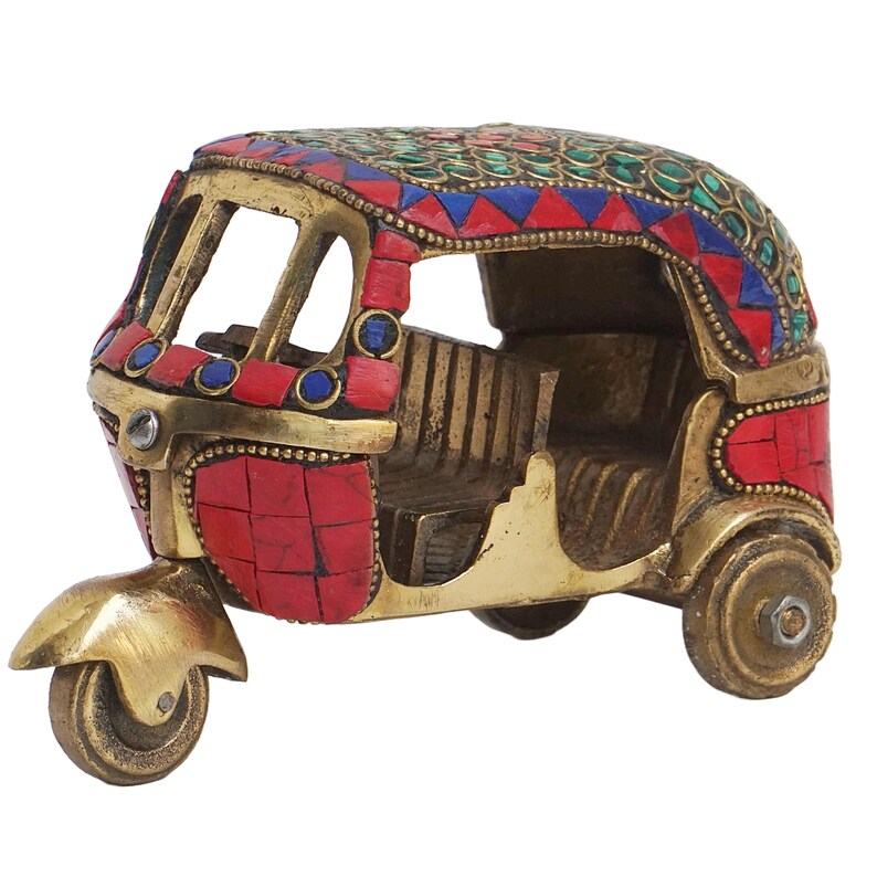 May include: A small, brass auto rickshaw figurine with a red, blue, and green mosaic design. The figurine has a detailed interior and three wheels.
