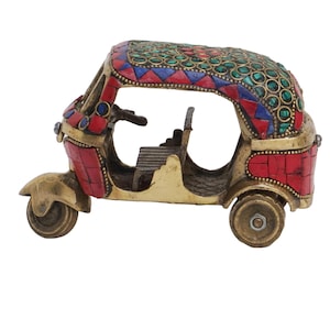 May include: A brass auto rickshaw figurine with a colorful mosaic design. The rickshaw is decorated with red, green, and blue mosaic tiles. The figurine is a traditional Indian design.