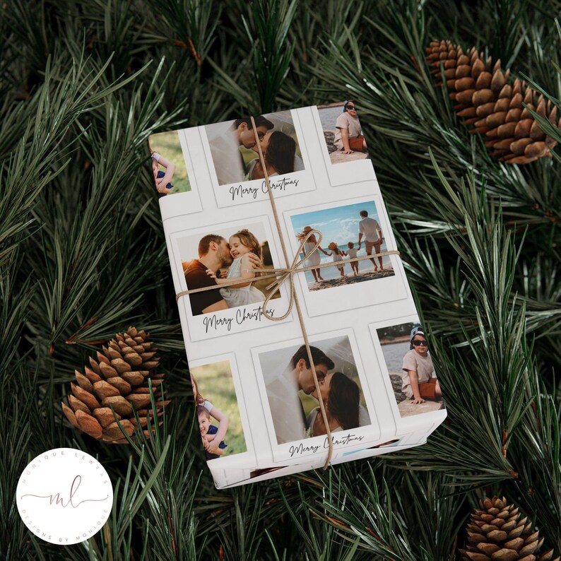 May include: A wrapped gift with a white background featuring family photos in polaroid-style frames. The words "Merry Christmas" are written in a script font. The gift is tied with twine and set against a backdrop of pine needles and pine cones.