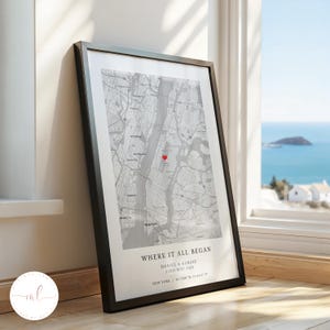 May include: A black and white map print with a red heart marking a location in New York City. The text below the map reads "Where it all began" with the names "Daniel & Karlee" and the date "23rd May 2024". The text also includes the location "New York" and the coordinates "40.7128° N, 74.0060° W".