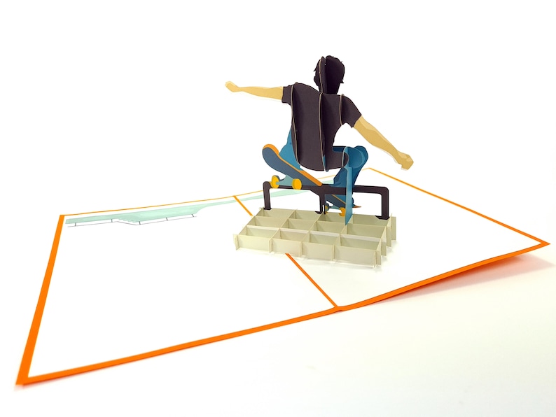 May include: A pop-up card featuring a person skateboarding over a ramp. The card is open and the person is in mid-air, with the skateboard wheels touching the ramp. The card is white with an orange border.