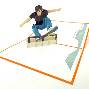 May include: A 3D pop-up card featuring a person skateboarding on a ramp. The card is white with an orange border and a green ramp in the background.