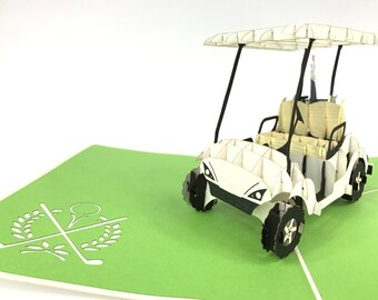 Puede incluir: Una tarjeta de golf pop-up de color blanco con fondo verde. La tarjeta presenta una bola de golf y dos palos de golf cruzados con coronas de laurel.