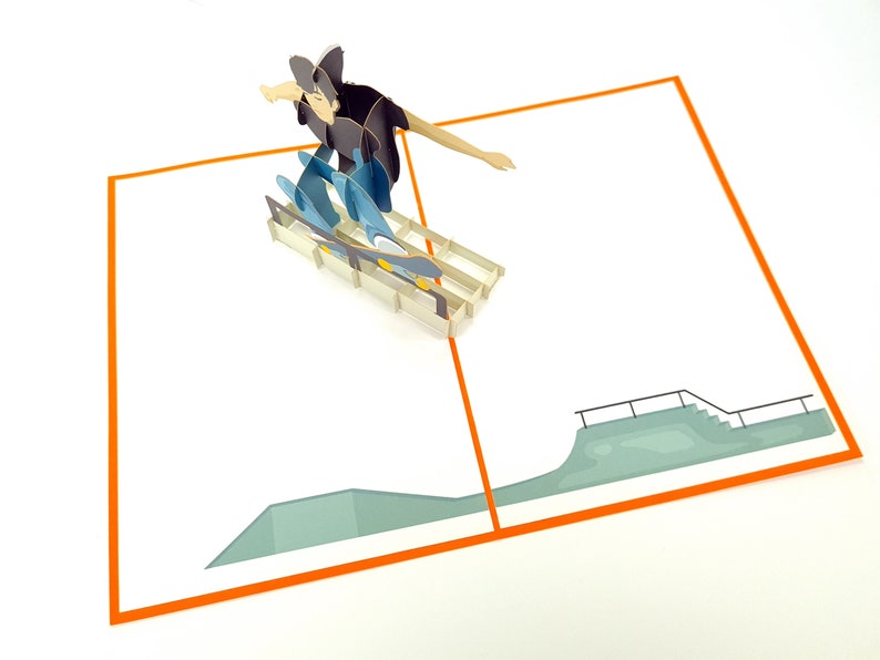 May include: A pop-up card featuring a person skateboarding on a ramp. The card is open and the person is in mid-air, with the skateboard underneath them. The card is white with an orange border and a green ramp.