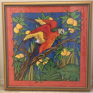 May include: A framed square art print featuring a vibrant macaw with red, yellow, and blue feathers perched on a brown tree branch. The background displays a blue sky, green tropical leaves, and yellow citrus fruits, all enclosed in a gold frame.