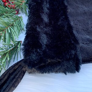 May include: Black faux fur stocking with a black velvet cuff. The stocking is made of soft, plush fabric and has a classic stocking shape.