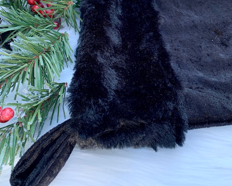 May include: Black faux fur stocking with a black velvet cuff. The stocking is made of soft, plush fabric and has a classic stocking shape.
