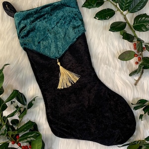 May include: A black velvet Christmas stocking with a teal velvet cuff and a gold tassel.