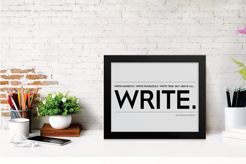 May include: A black framed poster with white text that reads 'WRITE HONESTLY. WRITE FEARLESSLY. WRITE TRUE. BUT ABOVE ALL... WRITE.' The text 'THE WRITING MANIFESTO' is in smaller font below the word 'WRITE.'