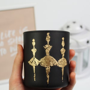 May include: Black glass candle holder with three gold ballerina silhouettes.