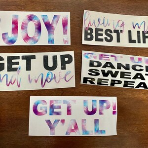 May include: Five colorful vinyl decals with motivational quotes. The decals feature tie-dye patterns in shades of pink, blue, and purple. The quotes include "Find the JOY!", "Living my BEST LIFE", "Get Up and Move", "Get Up! Dance Sweat Repeat", and "Get Up! Y'all".