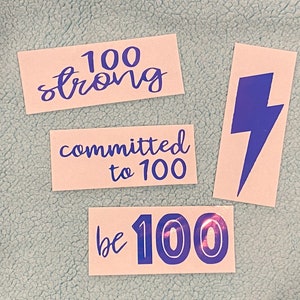 May include: Three pink paper stickers with blue text. The first sticker says "100 strong". The second sticker says "committed to 100". The third sticker says "be 100" with the number 100 in a bold blue font.